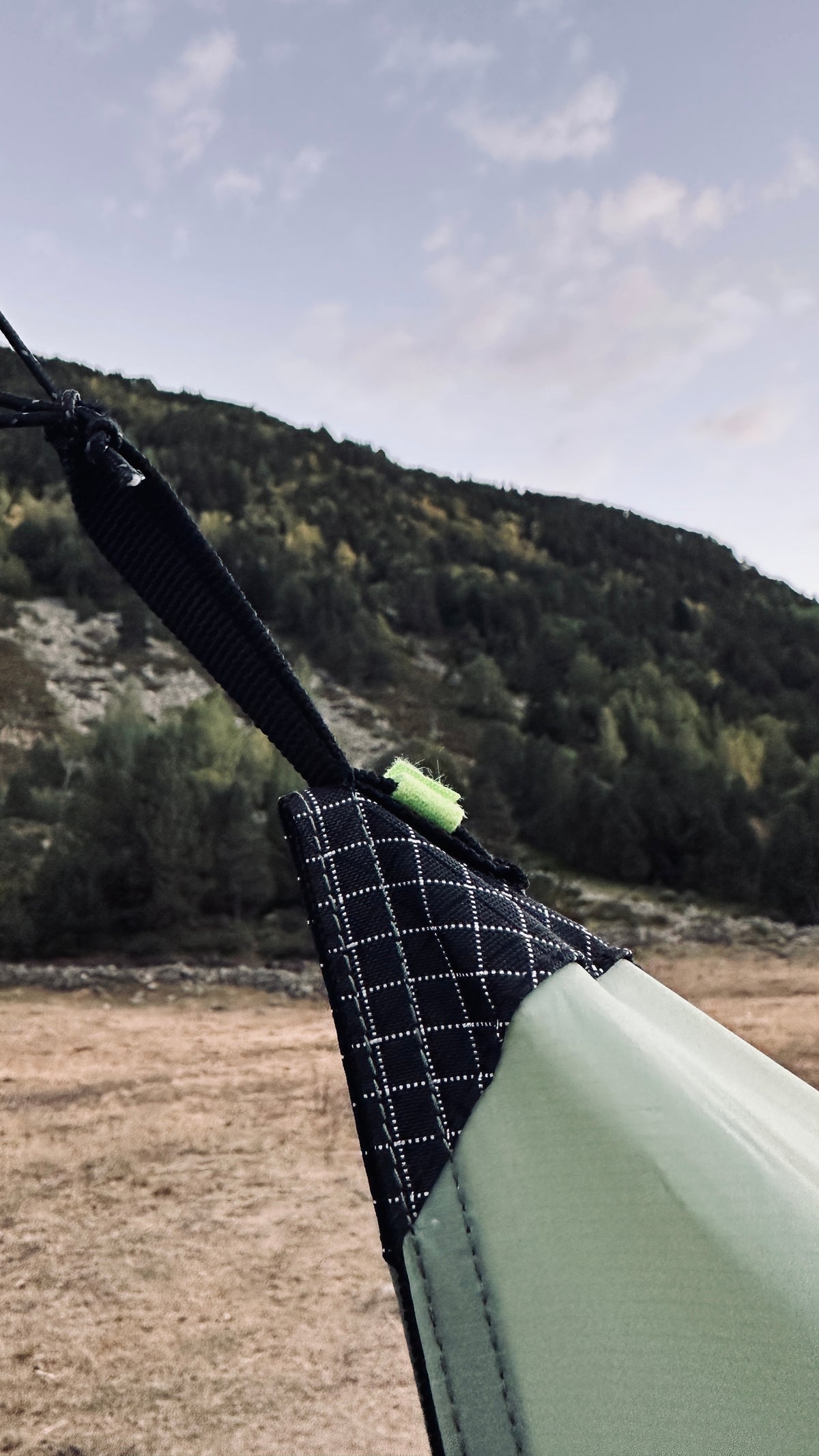 Detalle de un anclaje del Apex Tarp con refuerzo de Dyneema y velcro verde en la montaña